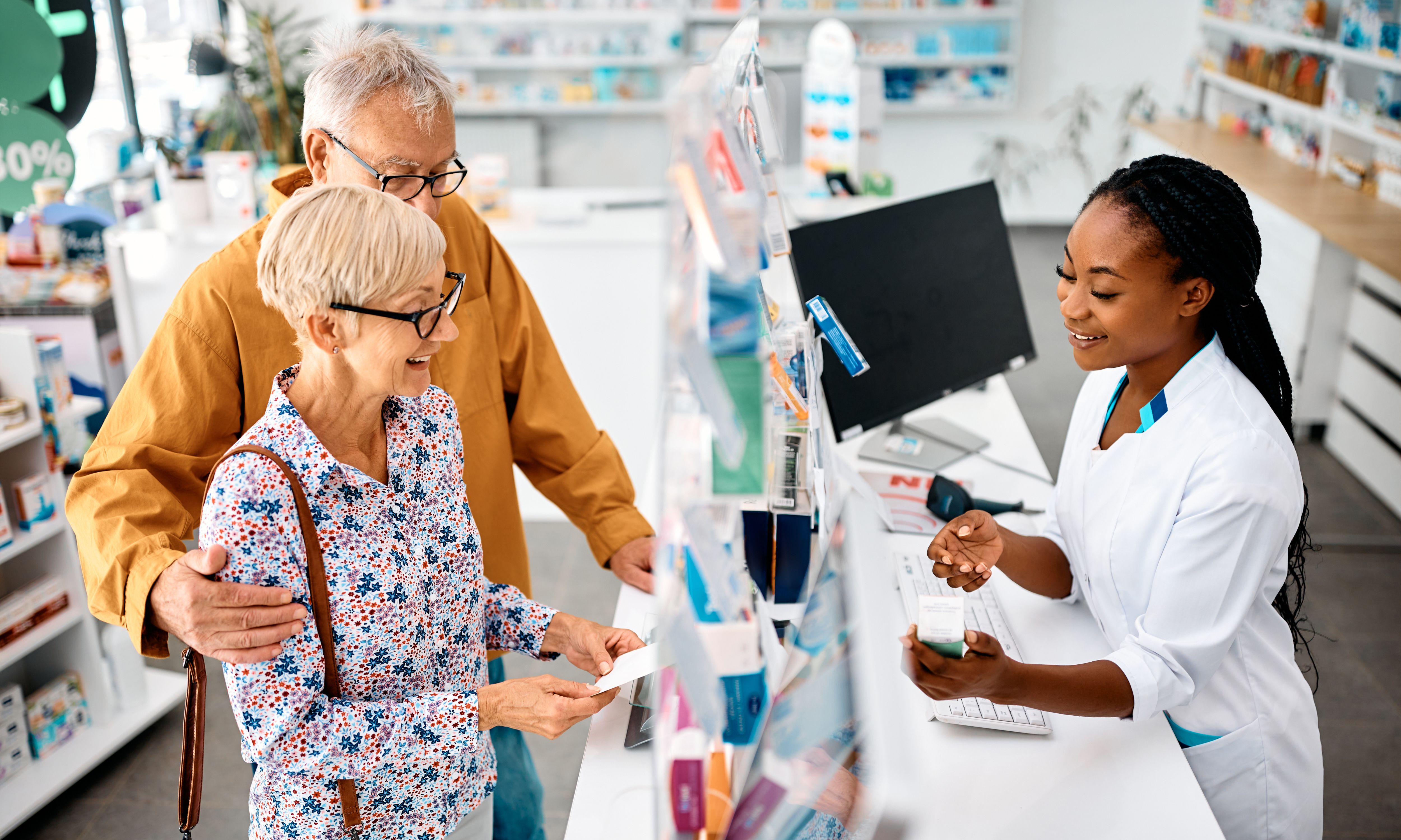 Pharmacy assistant helping older couple with medication